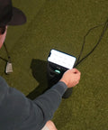 User interacting with indoor personal launch monitor with pay as you go software for realistic golf in garage or basement setup.