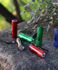 Assorted colored 20-Pack Aluminum 6-LED Flashlights Set with Lanyard, AAA Batteries Included, placed on a rock outdoors