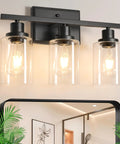 Three Light Black Vanity Light Fixtures With Clear Glass Shades above a mirror showing a hallway reflection