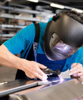 Welder using ER70S-6 Tig Welding Rod For Mild Steel 1/8x16 5 lb, copper coated carbon steel, in industrial setting.