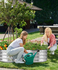 Two women gardening in a Raised Garden Bed Kit 2x2x1ft Galvanized Outdoor Planter Boxes With Easy Assembly For Vegetables, Fruits, And Flowers