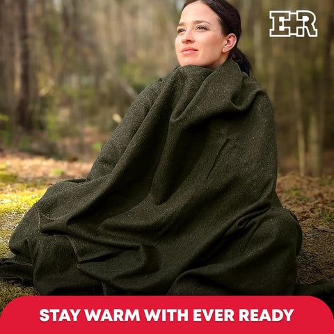 Person wrapped in Hardcore Wool Blanket For Outdoors And Survival, 80 Percent Wool, olive drab green, sitting outdoors.