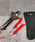 Scalable Tai Chi Training Sword Kit With Storage Pouch, featuring ornate handle detail, pouch alongside red tassels on grey fabric.