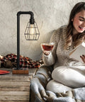 Woman reading next to Industrial Style Touch Control Table Lamp With LED Bulb Included, 3 Way Dimmer, 2 USB Ports And AC Outlet.