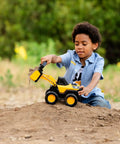 Child playing with Real Steel Wheel Loader Toy With Real Working Loader Arm And Durable Steel Parts in a dirt setting