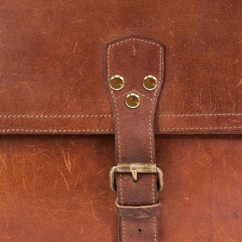Close-up of heavy duty copper binding screws with golden tone on a leather bag, showcasing sturdy alloy design.