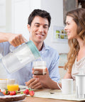 Couple using water filter replacement for Brita pitchers, NSF certified, in kitchen setting, pitcher on table