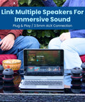 Ultra Portable Tiny But Mighty Mini Bluetooth Speaker With 3.5mm Aux Input Built In Mic And Plug And Play Ideal For Laptop MP3 Smartphone Or Any Device Compact Travel Sized Wireless Speaker Black Ready To Rock linked to laptop via AUX on a table outdoors next to people