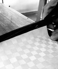 Close-up of hands cutting a checkered cloth material, suitable for Universal Piano Keyboard Dust Cover For 61 To 88 Keys Lightweight Adjustable.