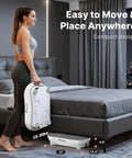 Person carrying Vibration Plate Exercise Machine with LED touchscreen, Bluetooth, and pull cord in a bedroom setting for home gym use