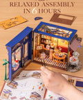 Openable Miniature Tea Room Book Nook Kit For Adults shown with assembly instructions, featuring a detailed tea-time scene model.