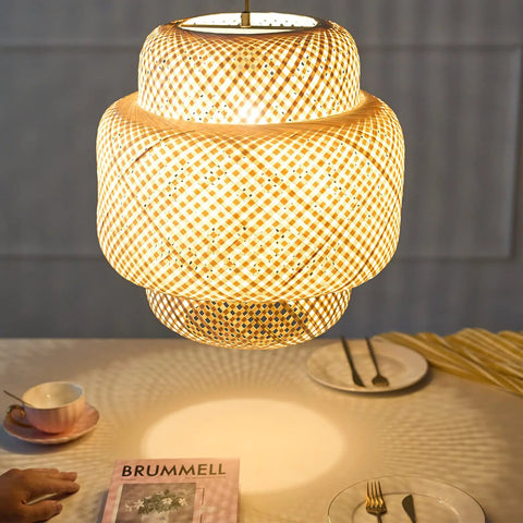 Hand Woven Boho Bamboo Pendant Light With Rattan Coastal Charm illuminating a dining table setup.