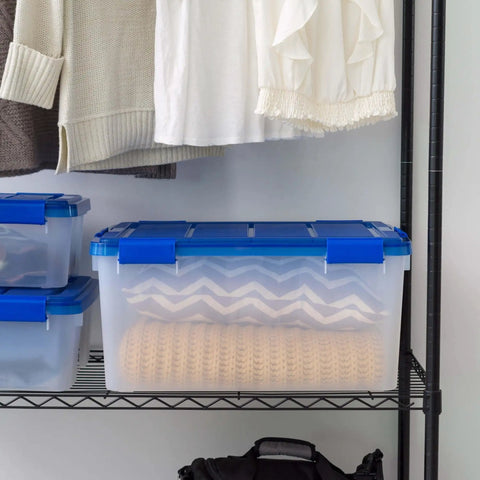 A 60-Quart Clear Airtight Storage Tote with Secure Latching Lid, stacked on a shelf, holding blankets in a closet.