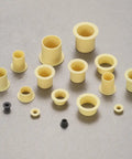 Four Piece Pack Of Precision Flanged Sleeve Bearings Crafted From High Grade Pom Plastic Providing Smooth As Butter Spin And A Dead Nuts Tight Fit For Hobbyist Builds And Equipment Repair Jobs, assortment of small yellow flanged bushings.