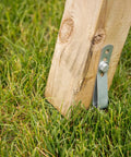 Wood post secured with Playset Anchor Kit For Swing Sets Heavy Duty Ground Anchors in grass, showing attached steel anchor and screw