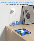 White USB-C to USB-C charging cable plugged into wall outlet beside a tablet on a wooden desk, 60W.