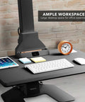 Heavy Duty Electric Standing Desk Converter With Monitor Mount And Wide Keyboard Tray sitting on a smooth surface with workspace essentials.