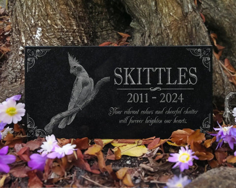 Granite Bird Portrait Memorial Stone Custom Engraved Marker For Parrots Canaries Finches Lovebirds, in garden setting with flowers.