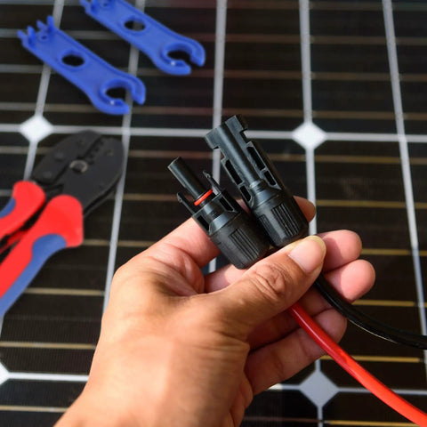 Hand holding connectors from Solar Wire Connectors Kit With Crimping Tool And Disconnect Tool 51 Piece PV Kit in front of tools