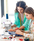 Two people using Beginner Friendly Mini Sewing Machine Kit With Finger Guard and accessory set on fabric project.
