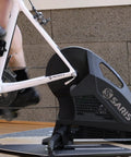 Indoor cycling setup featuring a quick release bike trainer skewer for rear wheel replacement, showing silver finish and alloy material.