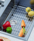 Heavy Duty Stainless Steel Kitchen Sink Grid Protector With Rear Drain Layout And Secure Hole Plug Fits Single Bowl Basins, featuring vegetables in sink.