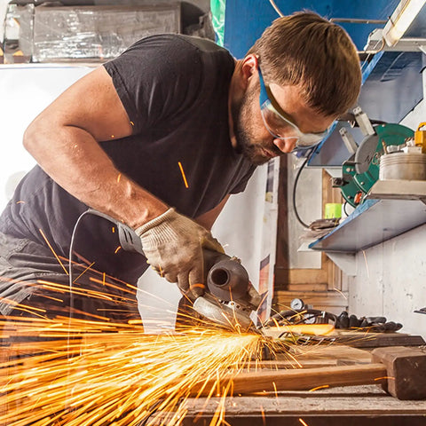 Man using power tool in workshop wearing Bulk Pack Of 96 Pairs Clear Safety Glasses With Six Color Frames For Adults Unisex Eye Protection Goggles