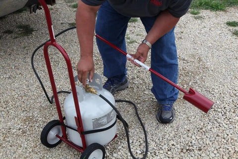 Person using Vapor Torch Kit With Squeeze Valve And Adjustable Pilot 500,000 BTU Propane Weed Burner for landscaping
