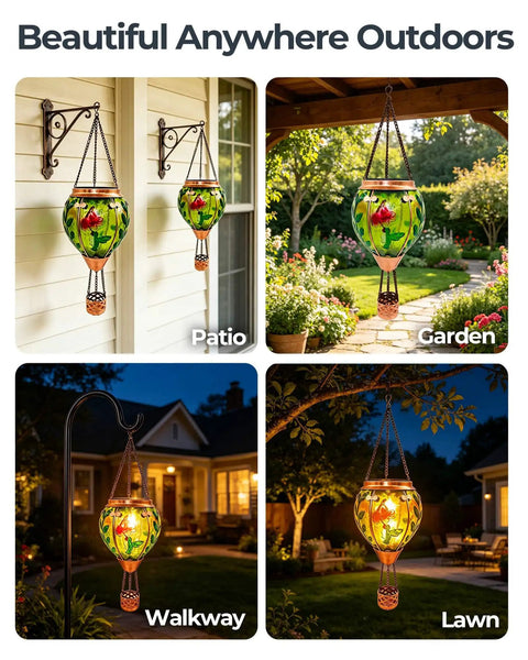 Glass Hot Air Balloon Solar Lantern With Flame Hand Painted Artwork Realistic Flickering Flame Hummingbird Accent Rustproof Metal Outdoor Solar Light For Garden Or Yard Easy Setup And Eco Friendly shown hanging in patio, garden, walkway, lawn at night.