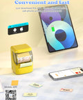 Hassle Free Bluetooth Label Maker With Straightforward Phone Sync And One Included Thermal Tape Roll Sweet For Quick Diy Crafting And Super Clean Home Tagging In Bright Yellow next to smartphone displaying label app.
