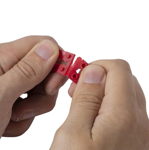 Person twisting apart a red piece from the GSP-24 24 Piece Twist-Apart Switch And Receptacle Spacers set.