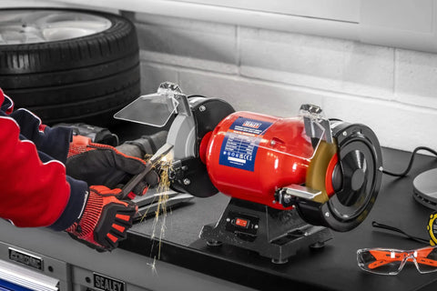 Workhorse 150Mm Bench Grinder Equipped With A Beefy 450W Induction Motor grinding metal with sparks flying.