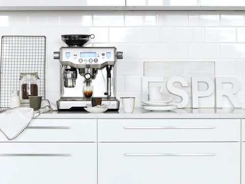 Oracle Fully Automatic Espresso Machine In Brushed Stainless Steel With 58 mm Portafilter on kitchen counter with coffee accessories.