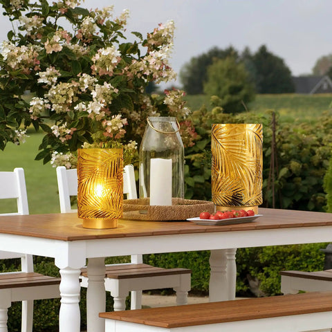Outdoor scene with Cordless Battery Operated LED Glass Lamp With Timer Yellow Table Centerpiece, glowing on wooden table.