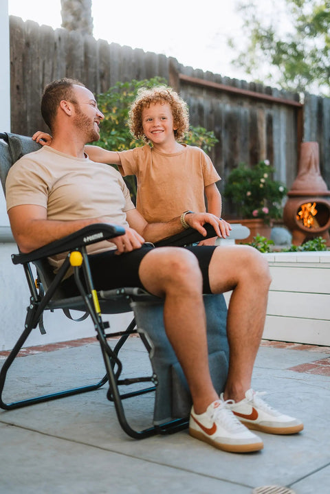 Man sitting in Legz Up Folding Outdoor Lounger With Adjustable Recline And Leg Elevation All In One Outdoor Chair for patio use.