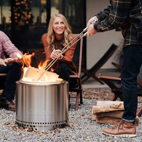 Person using Fire Pit Tools 2-Piece Set With 36.5 Inch Poker And 32 Inch Wood Tongs, Stainless Steel Grabber Tools For Outdoor Campfires