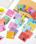 100 Pack Funny Sticky Notes for Work 3 by 3 Inches Sarcastic Self Adhesive Notepads with 25 Designs laid out on desk
