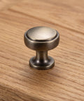 Close-up of a brushed zinc alloy cabinet pull on wood surface, part of 4 Pack Brushed Zinc Alloy Cabinet Pulls Single Hole Drawer Handles For Kitchen Cabinetry Bedroom Dresser Bathroom Vanity Wardrobe Hardware.