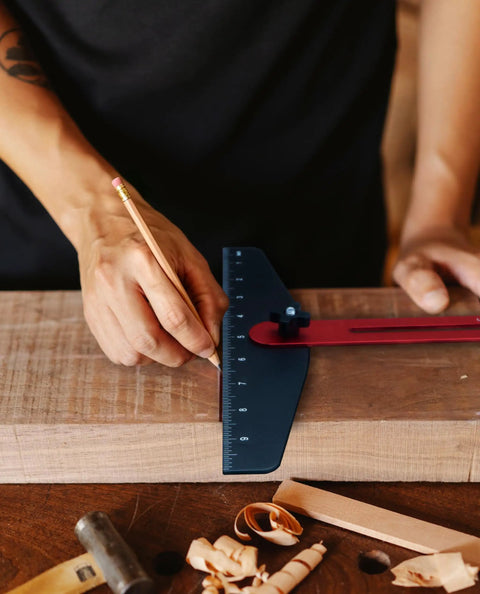 Person using Adjustable Stair Tread Template Angle Finder with heavy duty aluminum frame on wood for precise markings.