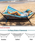 Woman relaxing on a striped hammock supported by a 12 Foot Hammock Stand For Two Built Tough, Heavy Duty Steel Frame Supports Up To 450 Lbs, Rust Resistant Black Finish, Portable Carrying Bag, Indoor Outdoor Patio Camping Gear, Durable Outdoor Hammock Stand on a beach.