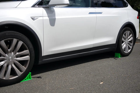 Heavy Duty Wheel Chocks Built Tough To Lock Your Rig Down Non Slip Safety Blocks For Rvs Trucks Trailers Campers Cars And Boats High Density Polypropylene Pair under a white car.