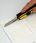 White high-temperature gasket paper sheet being cut with a utility knife; 1/8 in thick, 7x10 in