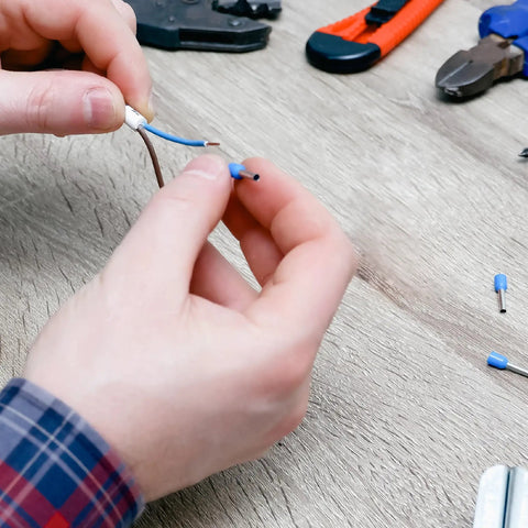 Person using Ferrule Crimping Tool Kit With Wire Crimper, Pro Grade Nylon Storage Container, And 1,200 Electrical Wire Connectors The Go To Electrician Tool Set For Home Improvement And DIY Projects on blue wire