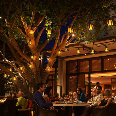 Evening cafe with Outdoor Solar String Lights 33Ft With 15 Realistic Flickering Flame Bulbs Waterproof Warm White For Patio Garden Yard Gazebo Bistro Cafe Party Decor Durable Led Accent Lighting Stay Lit hanging over a tree.
