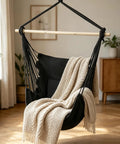 Cozy Hammock Chair With Two Cushions Hanging Rope Swing For Indoor Outdoor Patio Black Boho Macrame With Pocket And Hardware Kit Included Supports Up To 350 Lbs, showing black hammock chair with beige throw in living room.