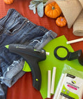 Cordless High Temperature Glue Gun 60W with standby base, glue sticks, and craft materials, including denim and burlap, on table