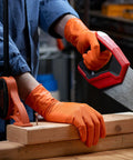 Heavy Duty 100 Count Orange Nitrile Gloves With Thick 8 Mil Industrial Build Featuring Rock Solid Grip And X Large Fit For Demanding Automotive Jobs That Deliver Real World Safety And Badass Durability in use while sawing wood.