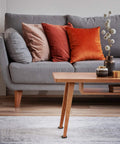 Gray sofa with colorful pillows next to a wooden table in a living room setting.
