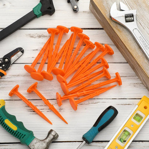 20 Pack 5 Inch Low Profile Survey Markers High Visibility Orange Yard Stakes with tools on wooden surface