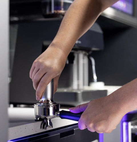Next Level Semi Automatic Espresso Machine With Built In Grinder Steam Frother, tamping coffee grounds in portafilter.